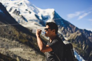 man drinking water bottle on a mountain