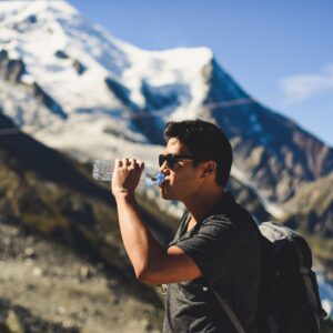 man drinking water bottle on a mountain